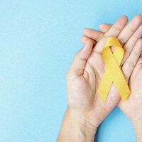 Mano sosteniendo un moño amarillo como símbolo de la prevención del suicidio.