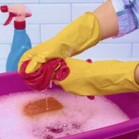 Una persona lavando ropa con guantes.