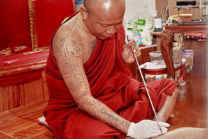 Persona realizando un tatuaje tradicional en Tailandia