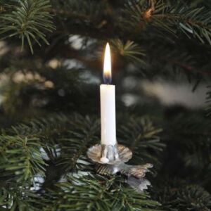 Una vela blanca con un candelabro plateado ilumina el árbol de navidad