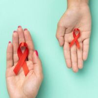 Dos manos con cinta roja de VIH