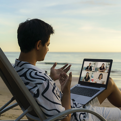 Hombre en la playa tomando una videollamada de trabajo